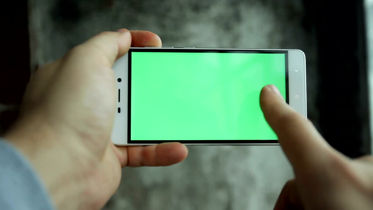 hombre de primer plano con la mano sosteniendo y tocando el teléfono con pantalla verde vertical