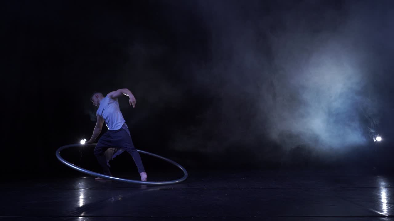 un acróbata muscular muestra trucos difíciles para el equilibrio y la concentración mientras gira en una rueda de cir