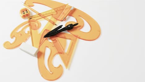 compass, pencil, sharpener, eraser and rulers with copy space on white background, slow motion