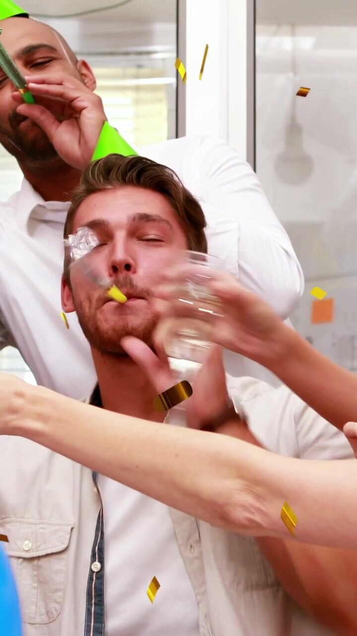 Vertical video: Seated man, team clinking flutes toasting in home party, cone hats confetti falling