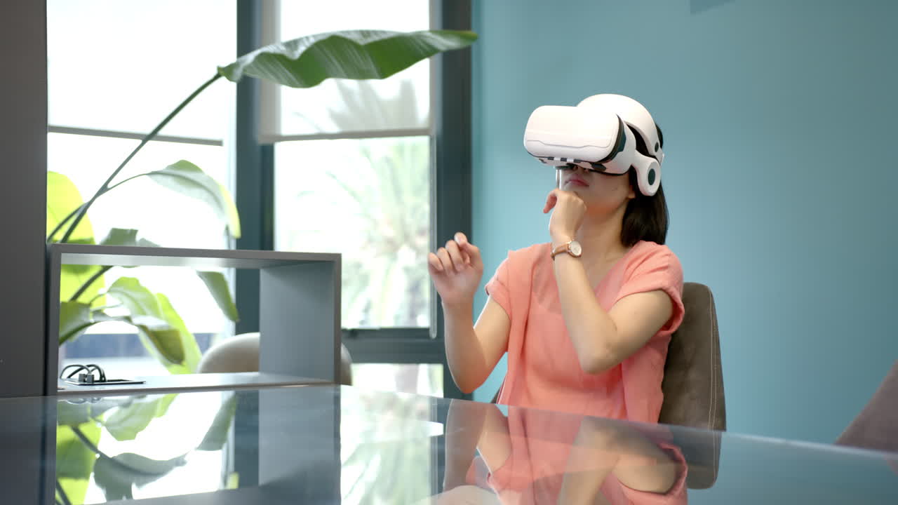 Using VR headset, woman sitting at desk in modern office environment