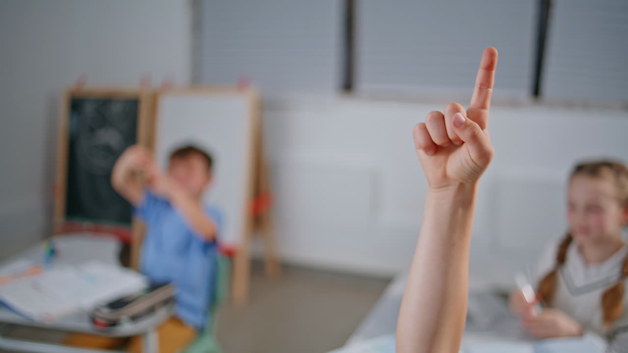 School kid raising hand at lesson closeup. Unrecognizable pupil child answering