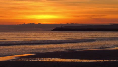 Cielo-Naranja-Del-Amanecer-Sobre-La-Orilla-Del-Mar-Con-La-Pared-Del-Puerto