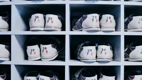 bowling rental shoes with visible size tags lined up inside white storage rack