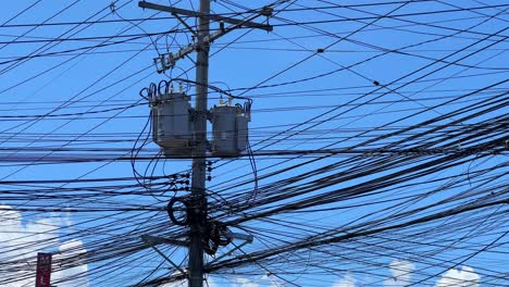 close-up of tangled electrical lines and transformers on a city pole under a clear sky—perfect for infrastructure, energy, or technology themes