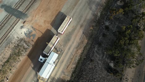 fotografía aérea de arriba hacia abajo de un camión de carga durante la distribución de grano cosechado en australia occidental