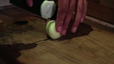 closeup shot of chef hands chopping onion on wooden cutting board