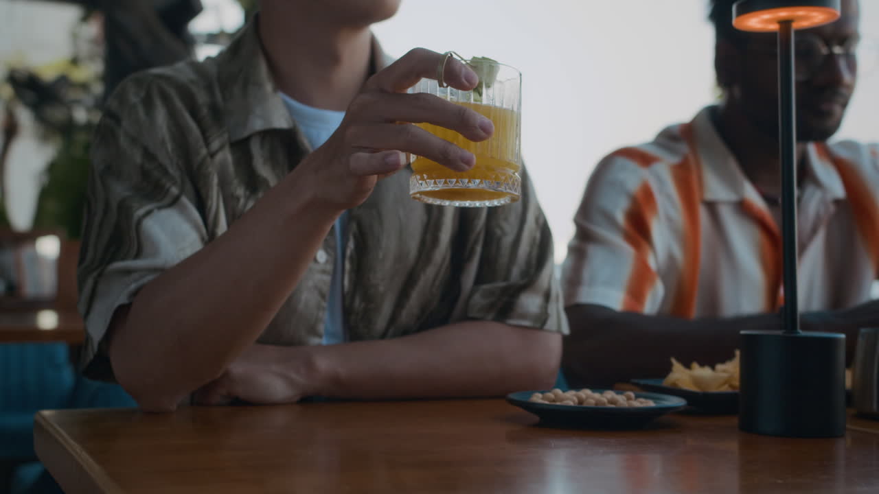 Vietnamese Man Drinking Cocktail and Chatting with Friends in Restaurant
