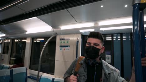 man wearing face mask while standing inside the moving train at the underground metro in montreal, quebec, canada