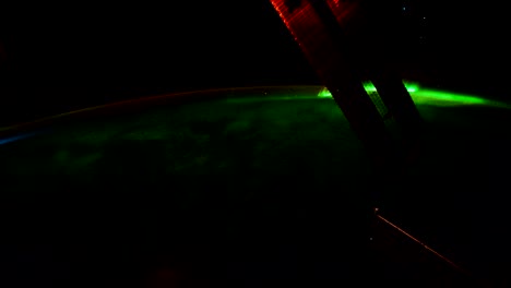 a bright green aurora as seen above the north pole of the planet earth.  solar panels from the iss are seen in the foreground.  stills courtesy of the earth science and remote sensing unit, nasa johnson space center.  processing by rebus_prod.
