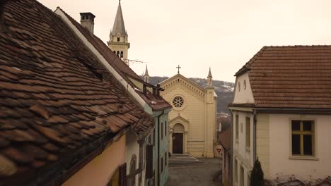 a dolly movement drone shot, amidst a vintage architechtural lane in a closed locality, with a church at the end of the lane with a cityscape in the background in an european city on an afternoon