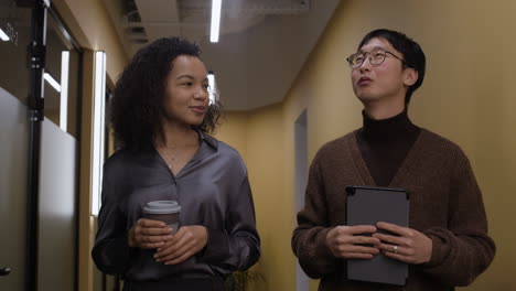 two colleagues in conversation in an office hallway