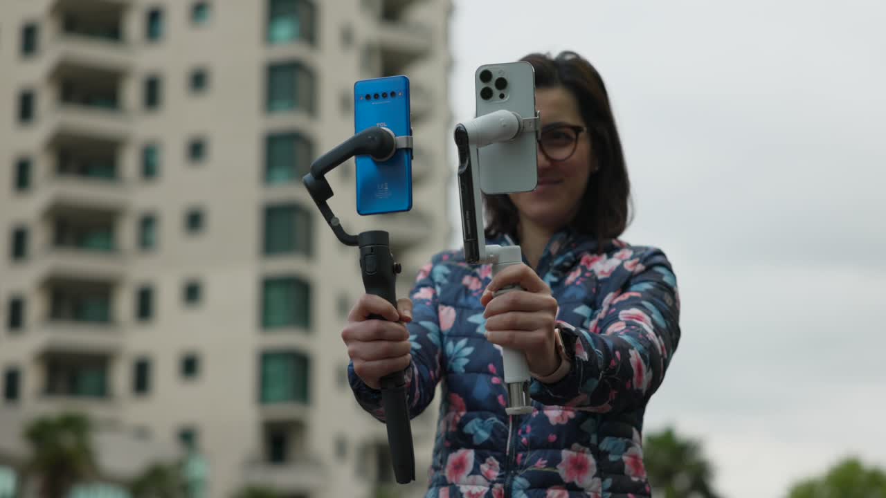 YouTuber e influencer professionista che tiene in mano due stabilizzatori gimbal con smartphone installato
