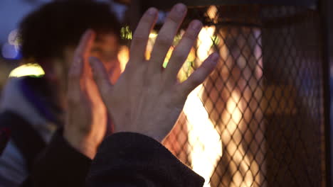 male friends warming hands on outdoor heaters at night