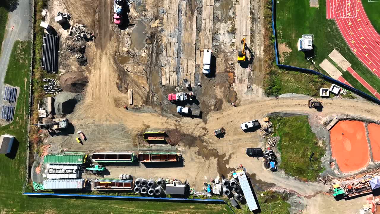 Downward aerial fly to a construction project with heavy vehicles on a developed area