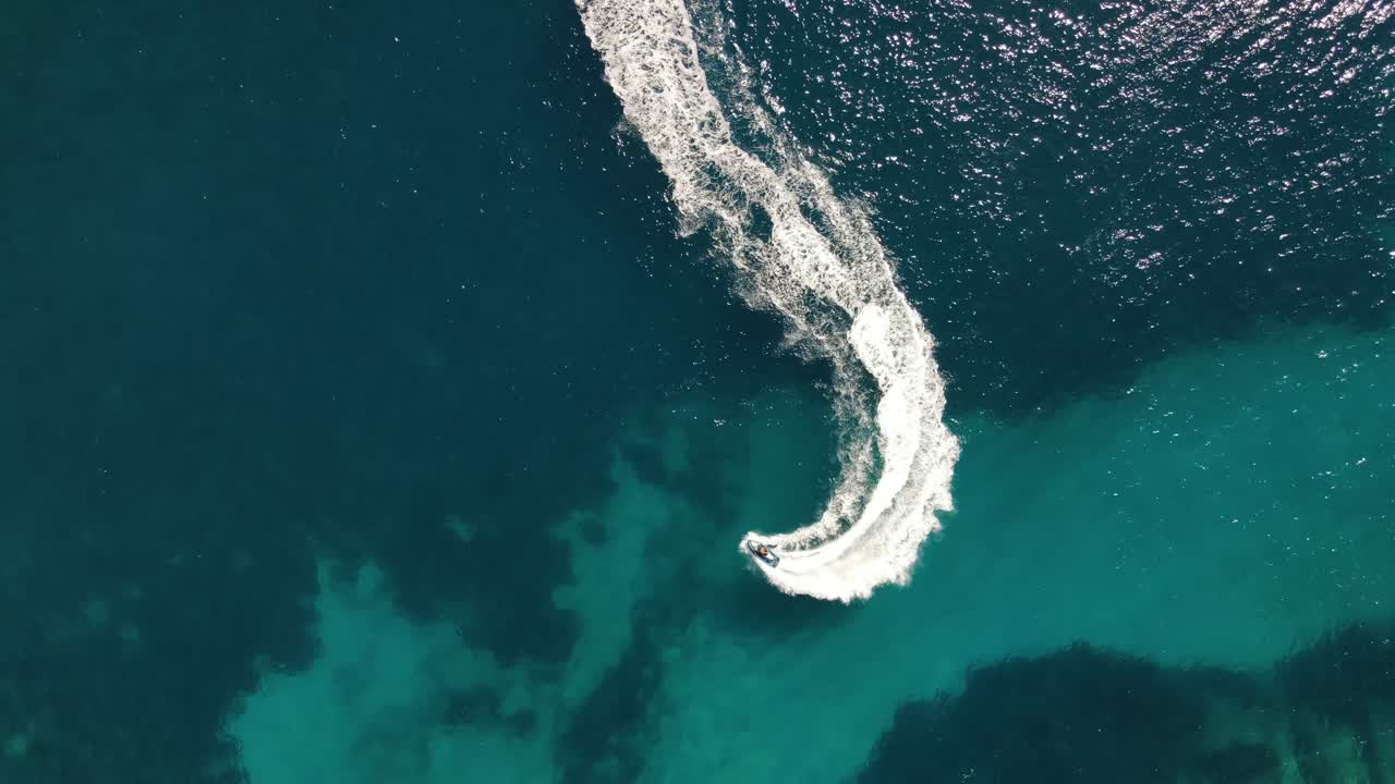 toma aérea por encima de varias motos acuáticas, dando vueltas en círculos y espuma blanca en el vasto mar azul cerca de ibiza, españa