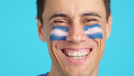 man with a salvadoran flag painted on the face smiling