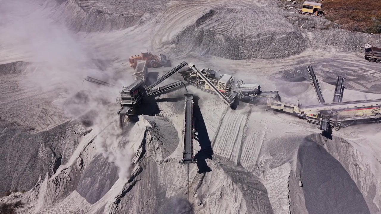 Large machinery works in a gravel pit during daylight hours