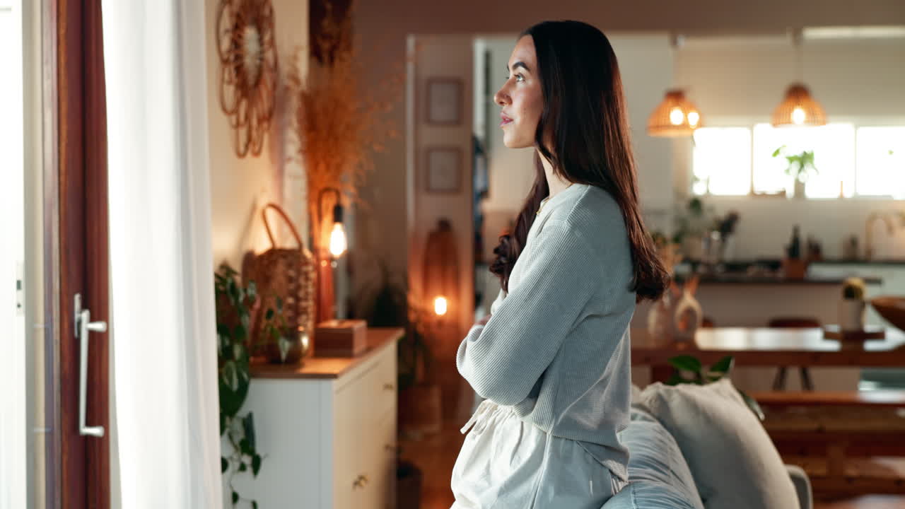 편안한 거실의 창밖을 바라보는 여자