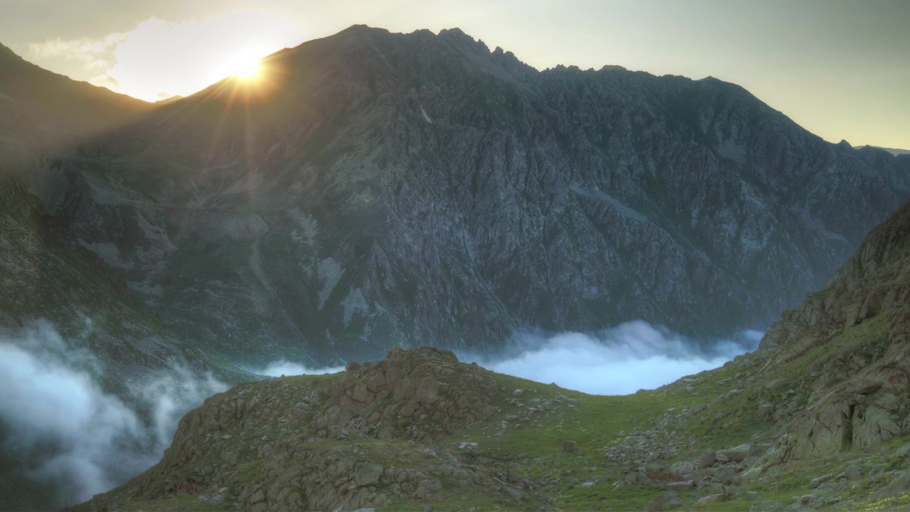 Coucher de soleil sur des sommets montagneux escarpés avec des nuages bas