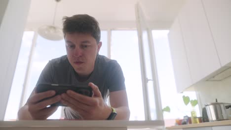 Man Playing Game on Phone While Doing Plank in Kitchen
