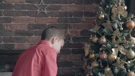 boy-looks-at-christmas-tree-with-golden-decorations