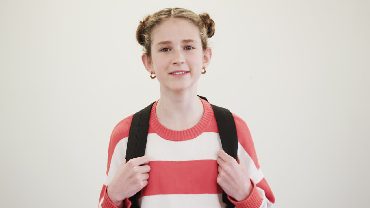 Smiling young girl with backpack wearing striped sweater, ready for school, copy space
