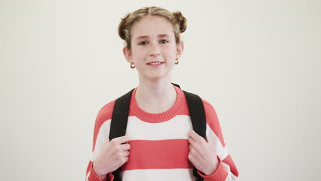 smiling young girl with backpack wearing striped sweater, ready for school, copy space