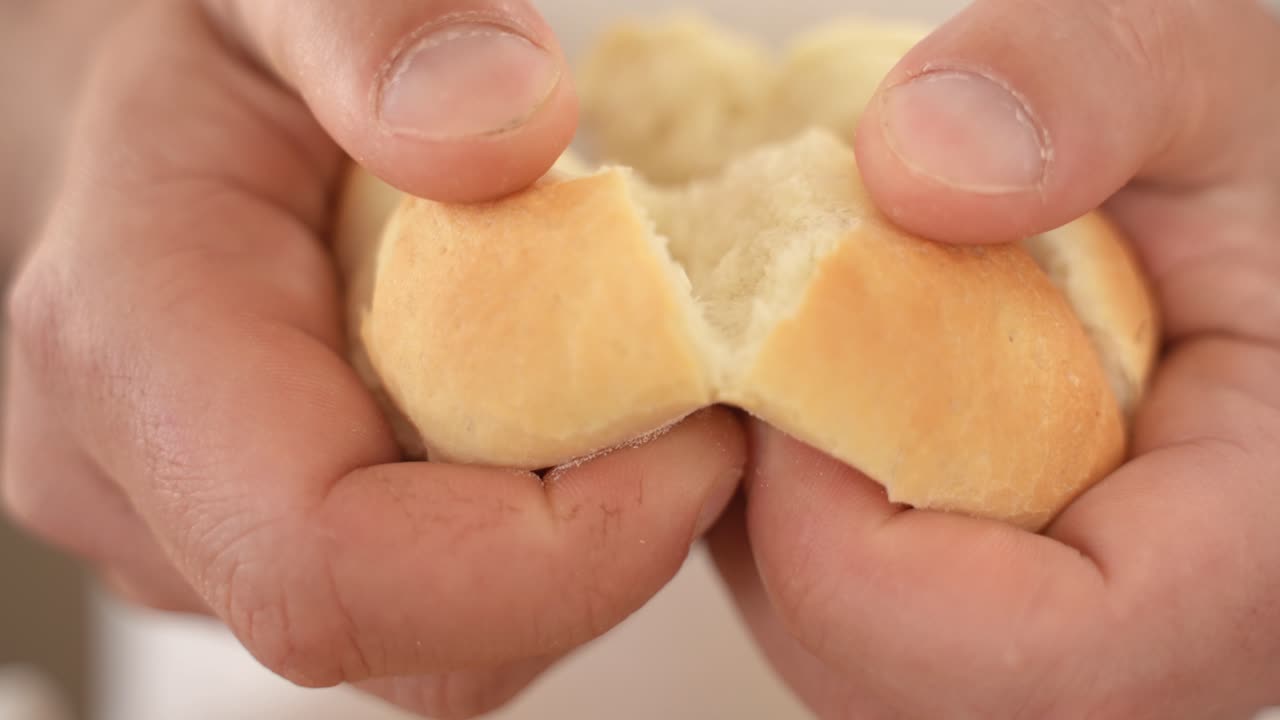 손으로 카이저 빵을 깨고 슬로우 모션이 복사 공간으로 닫힙니다.