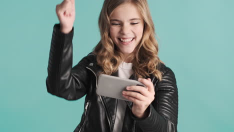 Teenage-Caucasian-girl-in-leather-jacket-playing-online-games-on-her-smartphone-and-winning.