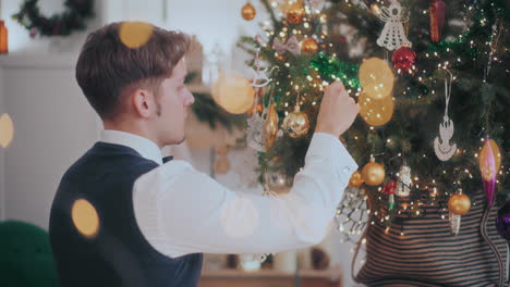 Hombre-Colgando-Chuchería-En-El-árbol-De-Navidad-En-Casa