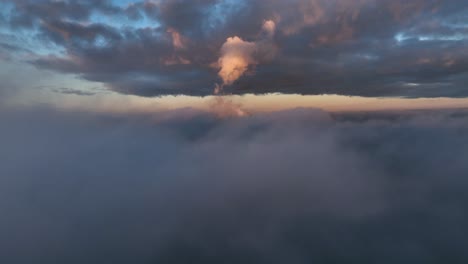 Vista-Aérea-Volando-Lentamente-Por-Encima-Y-A-Través-De-Las-Nubes-Con-El-Sol-Bajo-Y-Pintando-El-Cielo-En-Hermosos-Colores