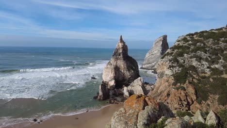 Schwenk-über-Den-Strand-Praia-Da-Ursa-Und-Die-Klippen-Mit-Rauer-See-Und-Blauem-Himmel