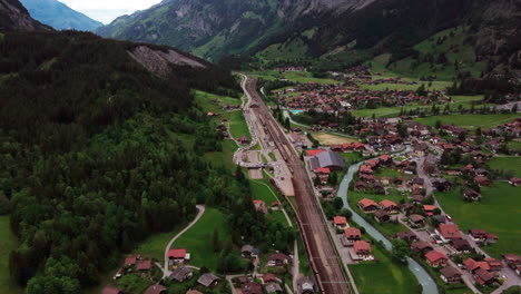 vuelo sobre un valle de montaña suizo alrededor de las vías del tren con un tren de coches para hacer cola para el túnel de lötschberg