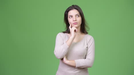 young beautiful woman thinking against green background