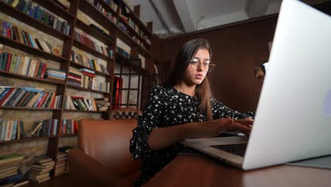 mujer trabajando en una computadora portátil en una biblioteca