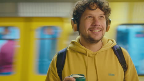 cheerful man in headphones listening to music in underground
