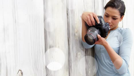 white spots floating against caucasian female photographer checking pictures in her digital camera