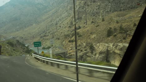 a river valley is displayed as a pov rv drives on a mountainous highway in the western united states