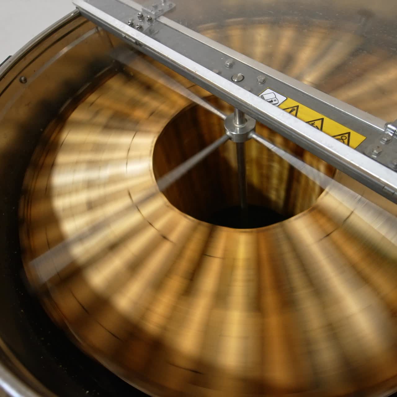 Centrifuge machine spinning the wooden frames to remove organic honey. Electric machine quickly rotating close up. Top view