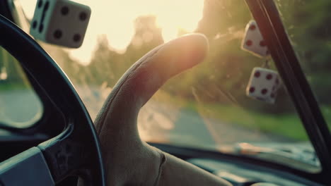 inside a vintage car driving at sunset with fuzzy dice