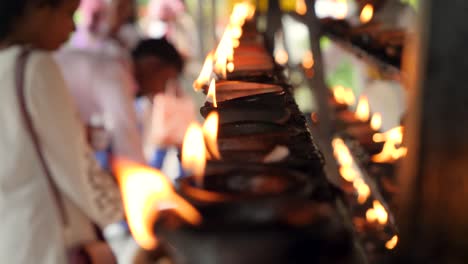 closeup 4k video of burning oil lamps and worshipping religious people in altar at buddhist temple