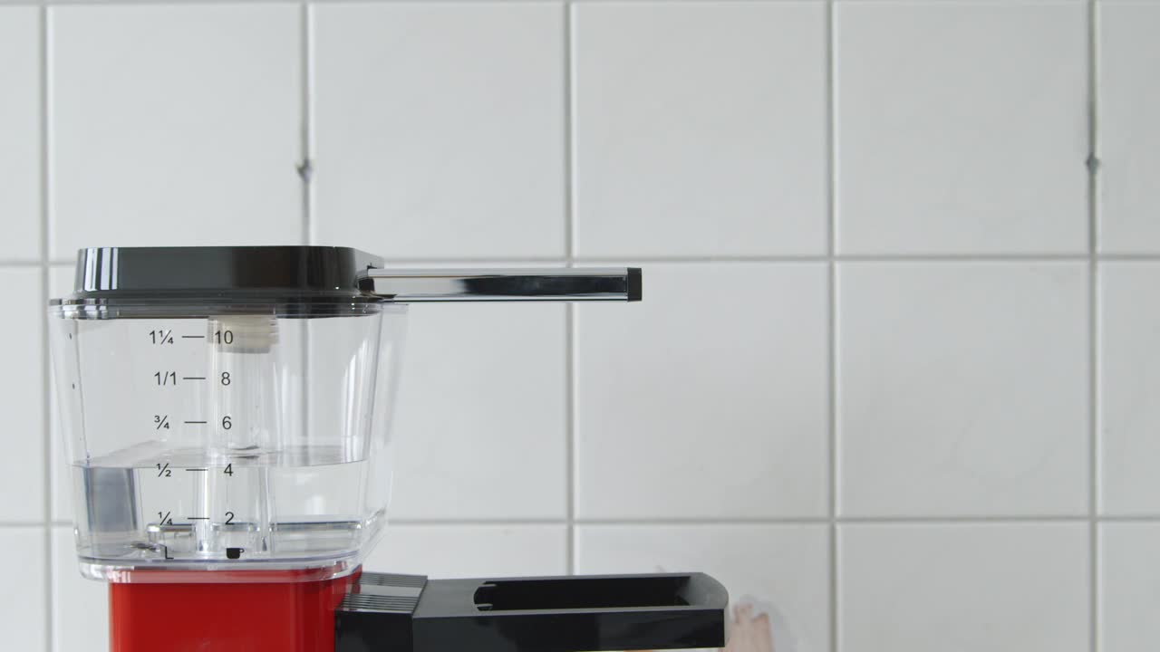 las manos caucásicas ponen el filtro en el portafiltros de una cafetera roja vintage