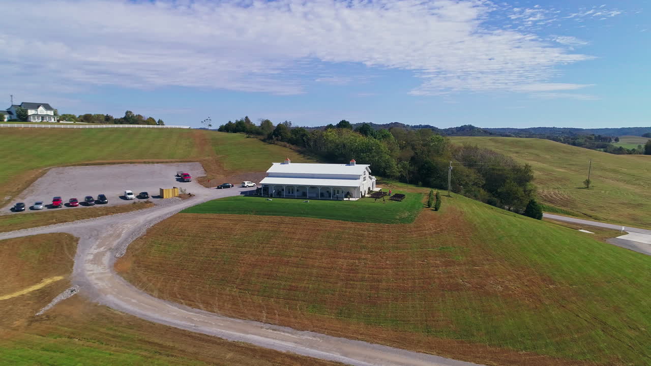 дневной самолет приближается к белому амбару на холме в живописной сельской местности, 4k