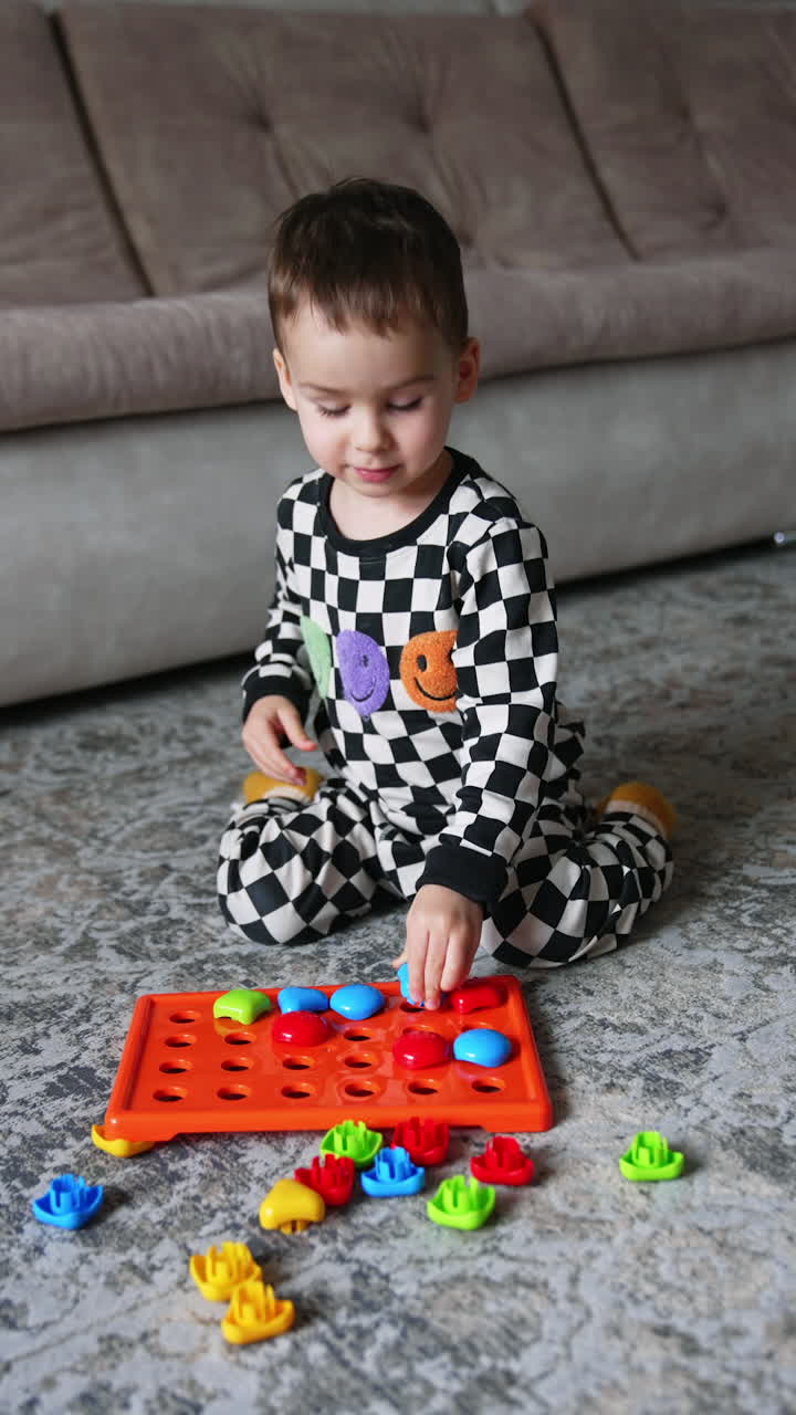 Small cute boy playing with toys on a floor. Educational play with colorful toys. Vertical video.