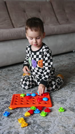 small cute boy playing with toys on a floor. educational play with colorful toys. vertical video.