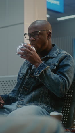 man eating a burger in an airport