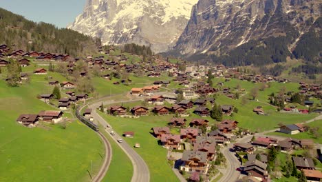 aerial drone footage pushing out with views of mountain train leaving grindelwald in swiss alps at 100% view