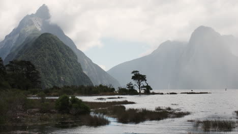 panorama of milford sound, majestic cloud-shrouded peaks rise from the depths of a mirror-like fiord