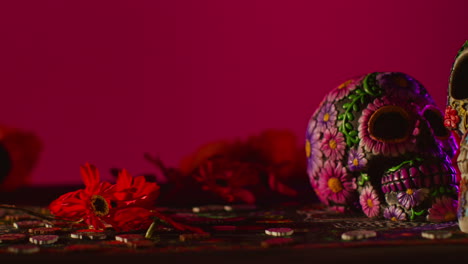 close up of decorated skulls and flowers celebrating mexican holiday of dia de muertos or day of the dead against red background 1